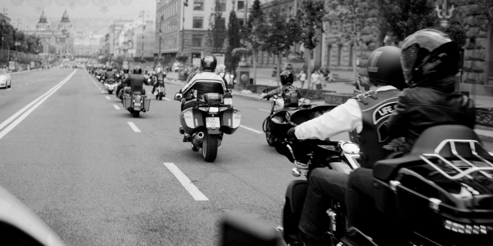 A group of Harley Davidson bikers riding down a city street.