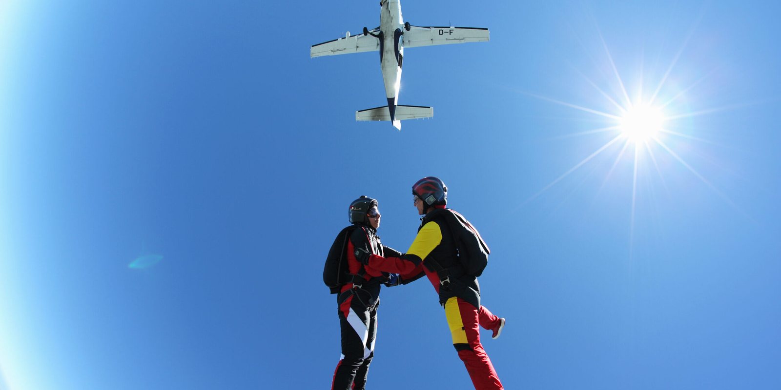 Two skydivers in freefall below a plane.